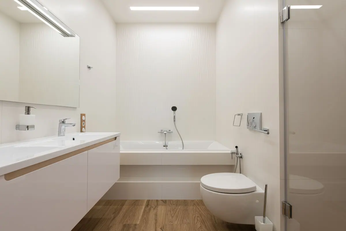 Baño luminoso con bañera, inodoro suspendido y mueble de bacha