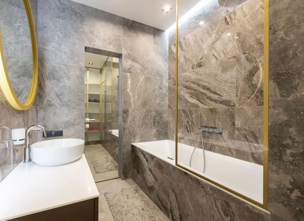 Baño revestido en mármol con bacha de apoyo y bañera