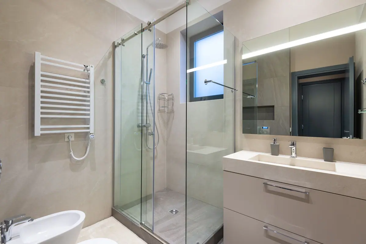 Baño moderno con mampara de vidrio, inodoro suspendido y mueble de bacha