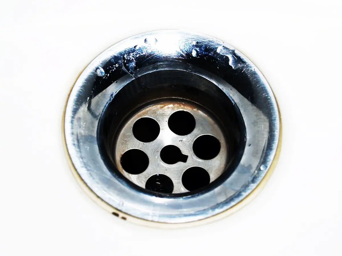Primer plano de un desagüe metálico de bacha con gotas de agua