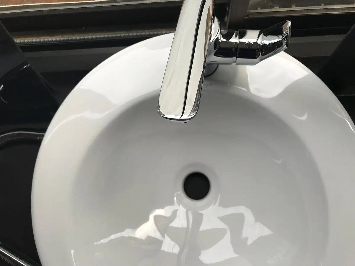 Bacha blanca de baño vista desde arriba con su desagüe y grifería cromada