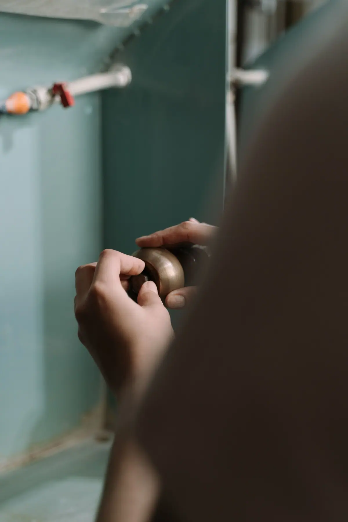 Manos ajustando una conexión de cañería debajo de una pileta de cocina